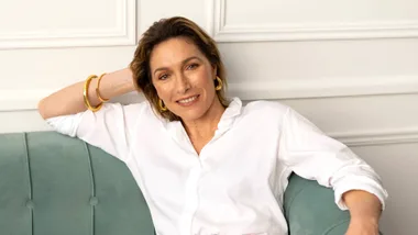 Woman sitting on a green couch with a colourful skirt