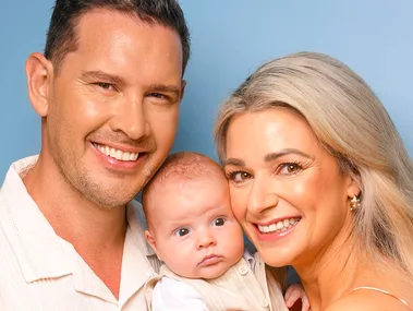 Zac and Erin holding baby Harley in front of a navy blue background