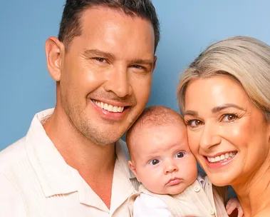 Zac and Erin holding baby Harley in front of a navy blue background