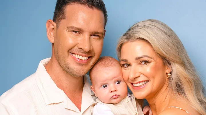 Zac and Erin holding baby Harley in front of a navy blue background