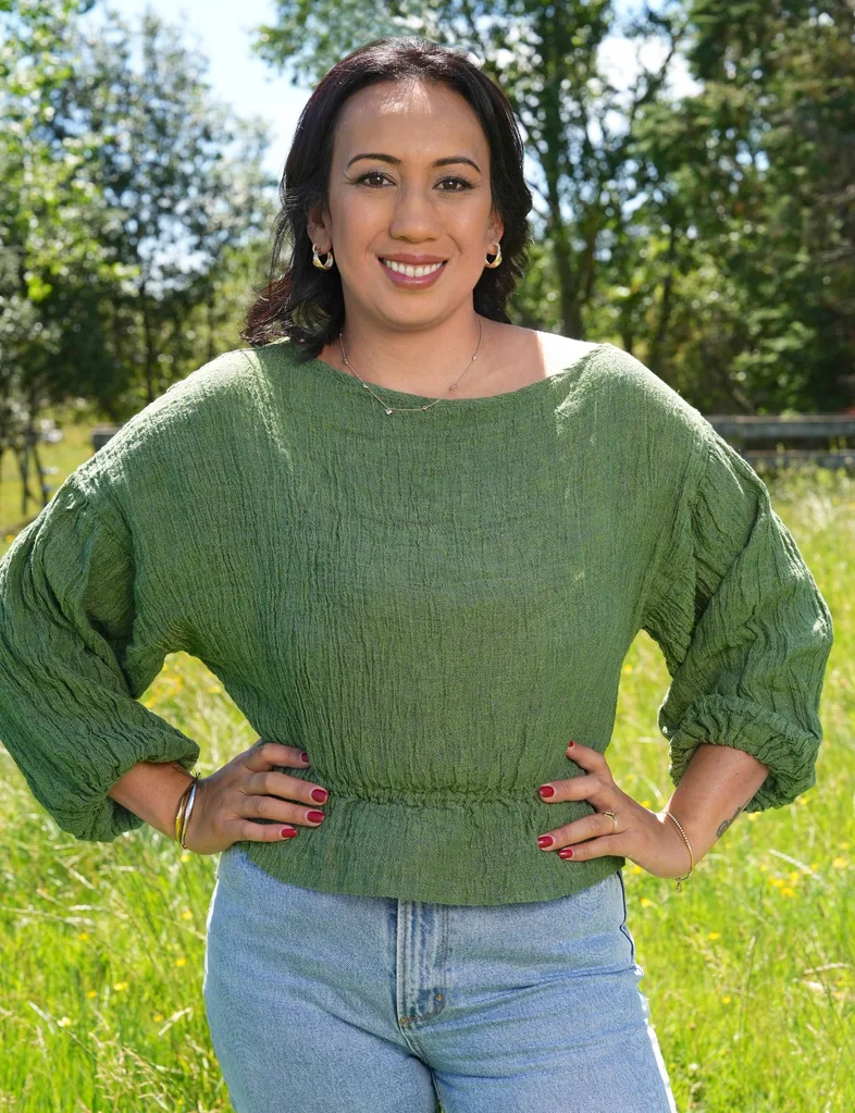 Lady with make-up and a greenn shirt, standing in a forrest