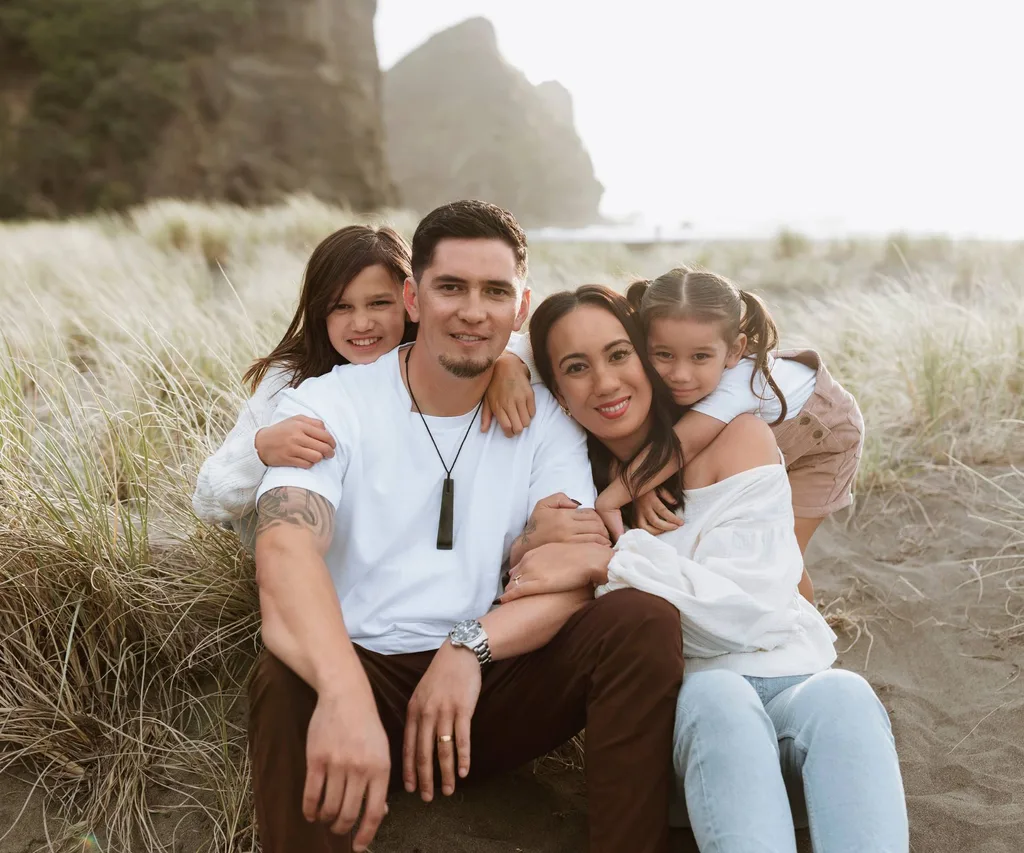 family sitting on a beach while the sun is setting