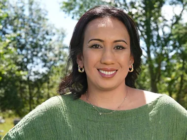 Lady with make-up and a greenn shirt, standing in a forrest