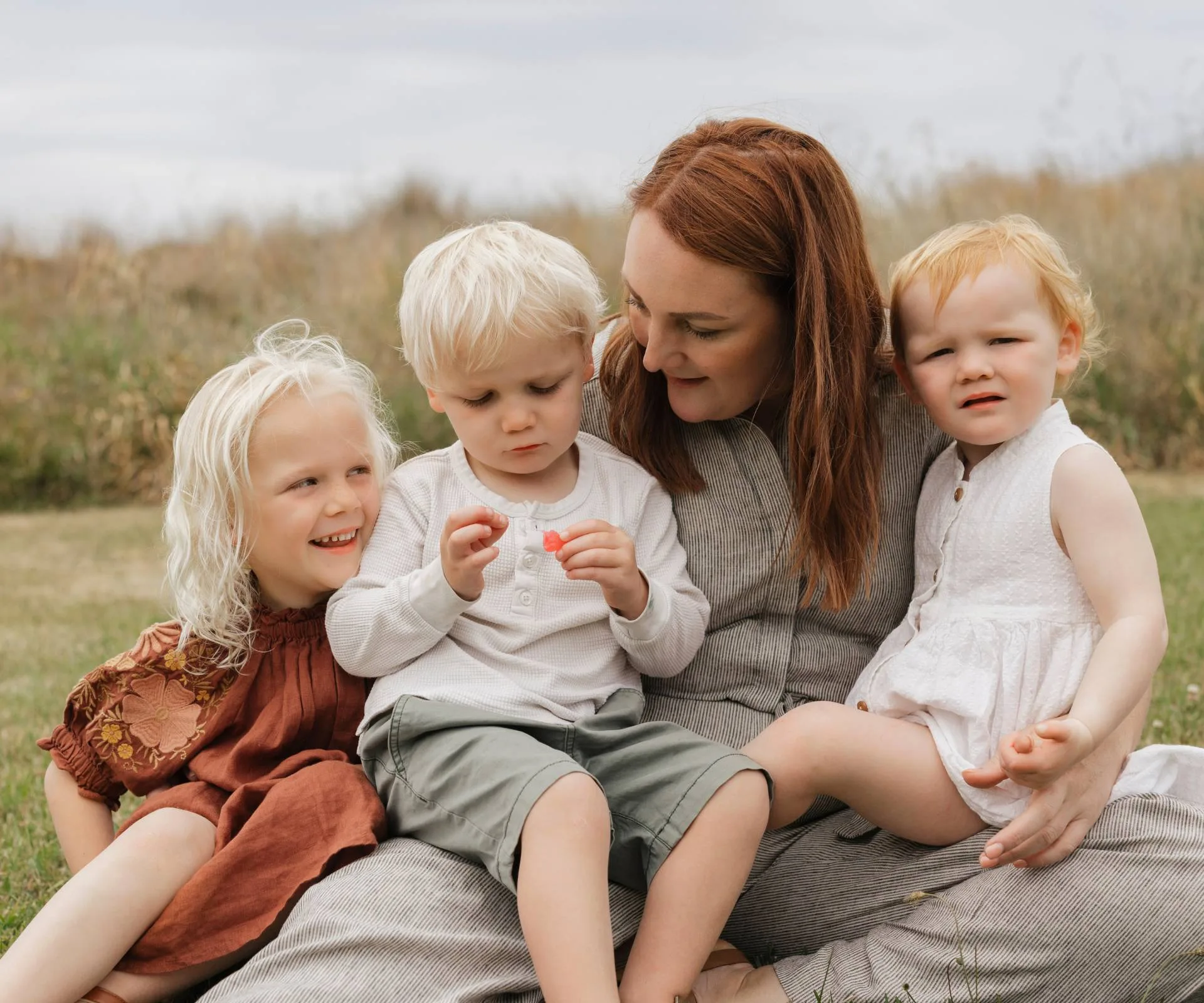 Alice with her three kids on a grassy patch outside