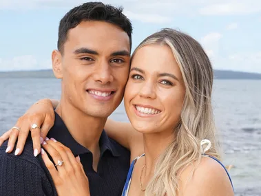 Max Mata and Greer Sinclair posing on a beach showing off the engagement ring