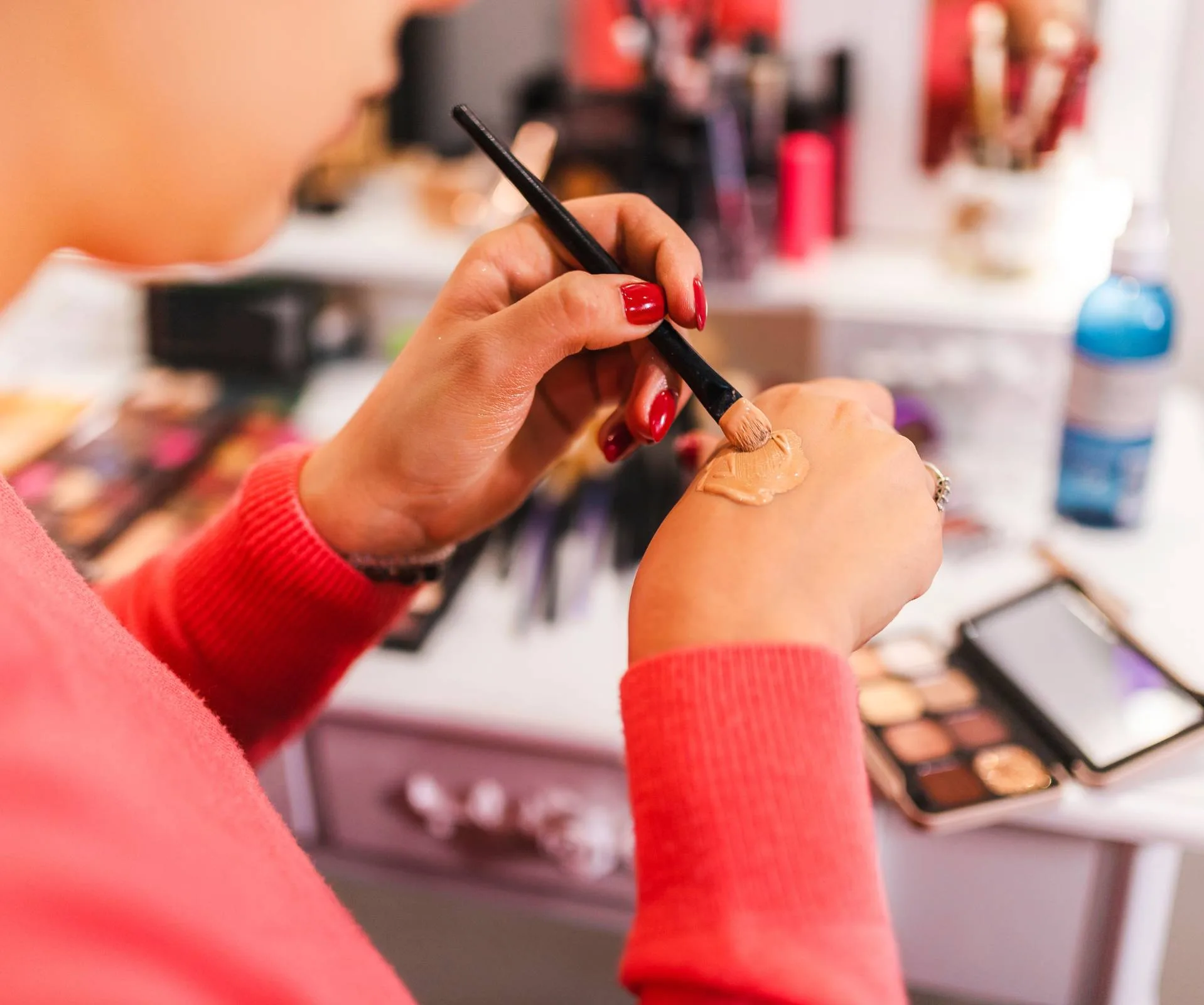 A woman mixing foundation with the brush on the back of her hand during her getting ready routine