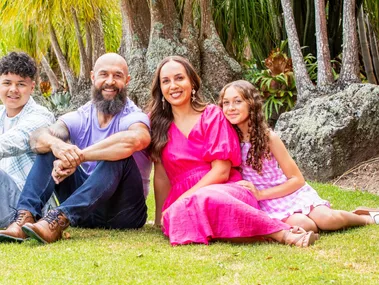 DJ Forbes sitting on some grass with his family