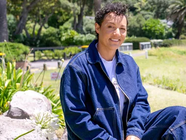 Kiri Allan sitting on a rock outside wearing double denim