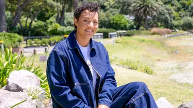 Kiri Allan sitting on a rock outside wearing double denim