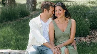 Nadia Lim sitting on a log with husband Carlos burying his face in her cheek