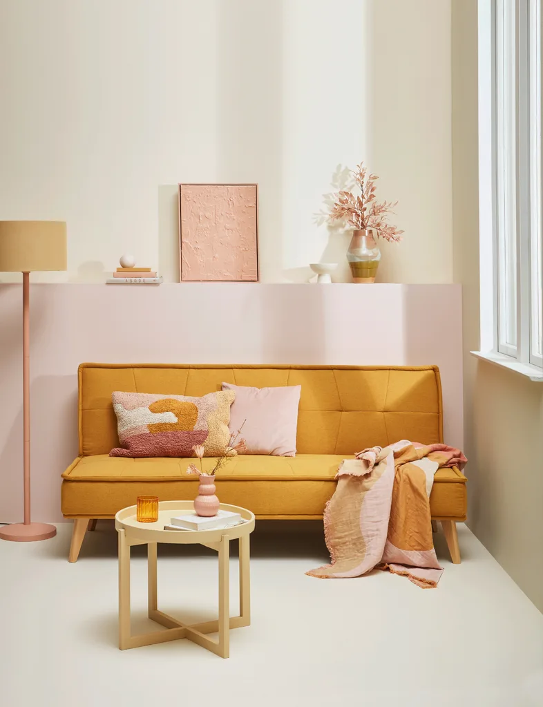 A golden couch makes the rosy pastel colours on the wall glow