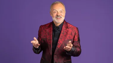 Graham Norton in front of a purple background