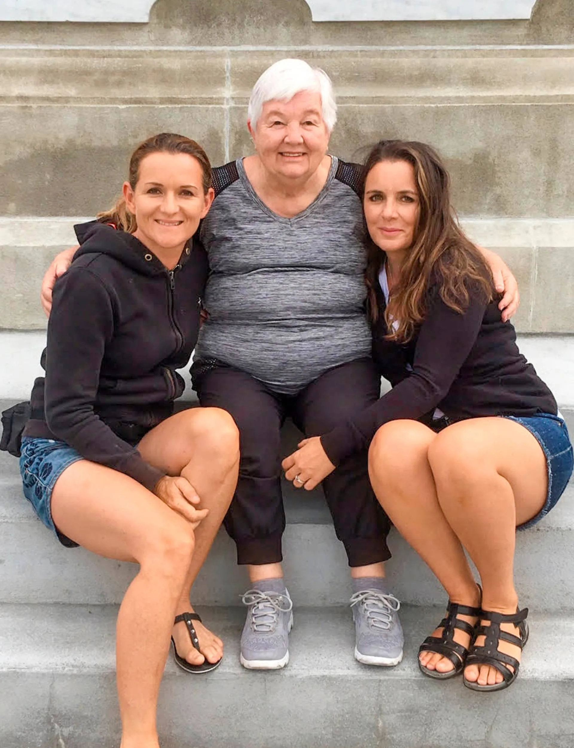 Avila Allsop sitting on outdoor concrete steps with her daughters
