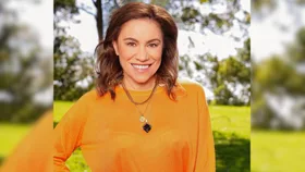 Stacey Morrison smiling in an orange sweatshirt