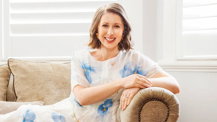 Lizzie Marvelly leaning on the arm of a leather couch