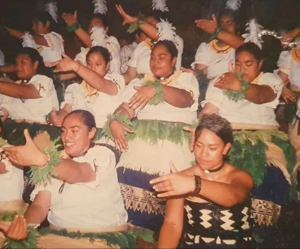 An old photograph taken of a group of Tongan women performing in traditional dress.