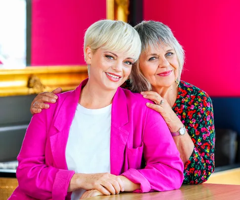 Laura Hill and Ginette McDonald standing next to each other wearing bright pink and bright florals
