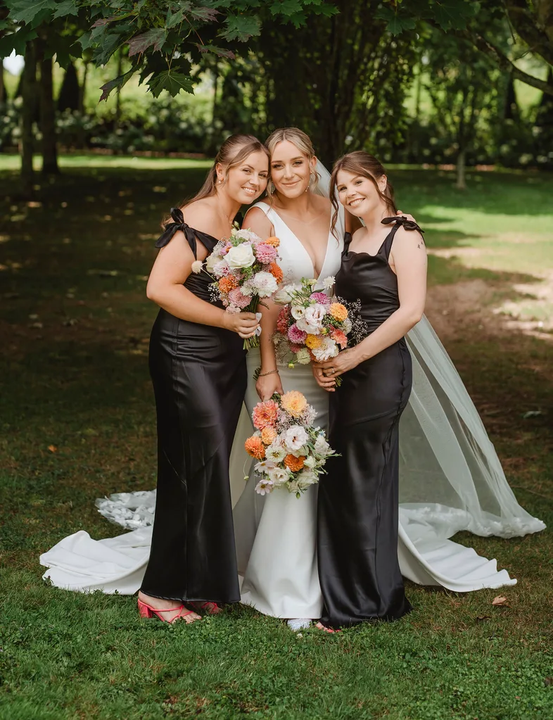 Bride with bridesmaids standing on either side in green dresses