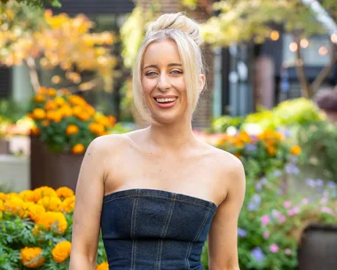 MAFS Jamie wearing denim jumpsuit with potted yellow flowers in background