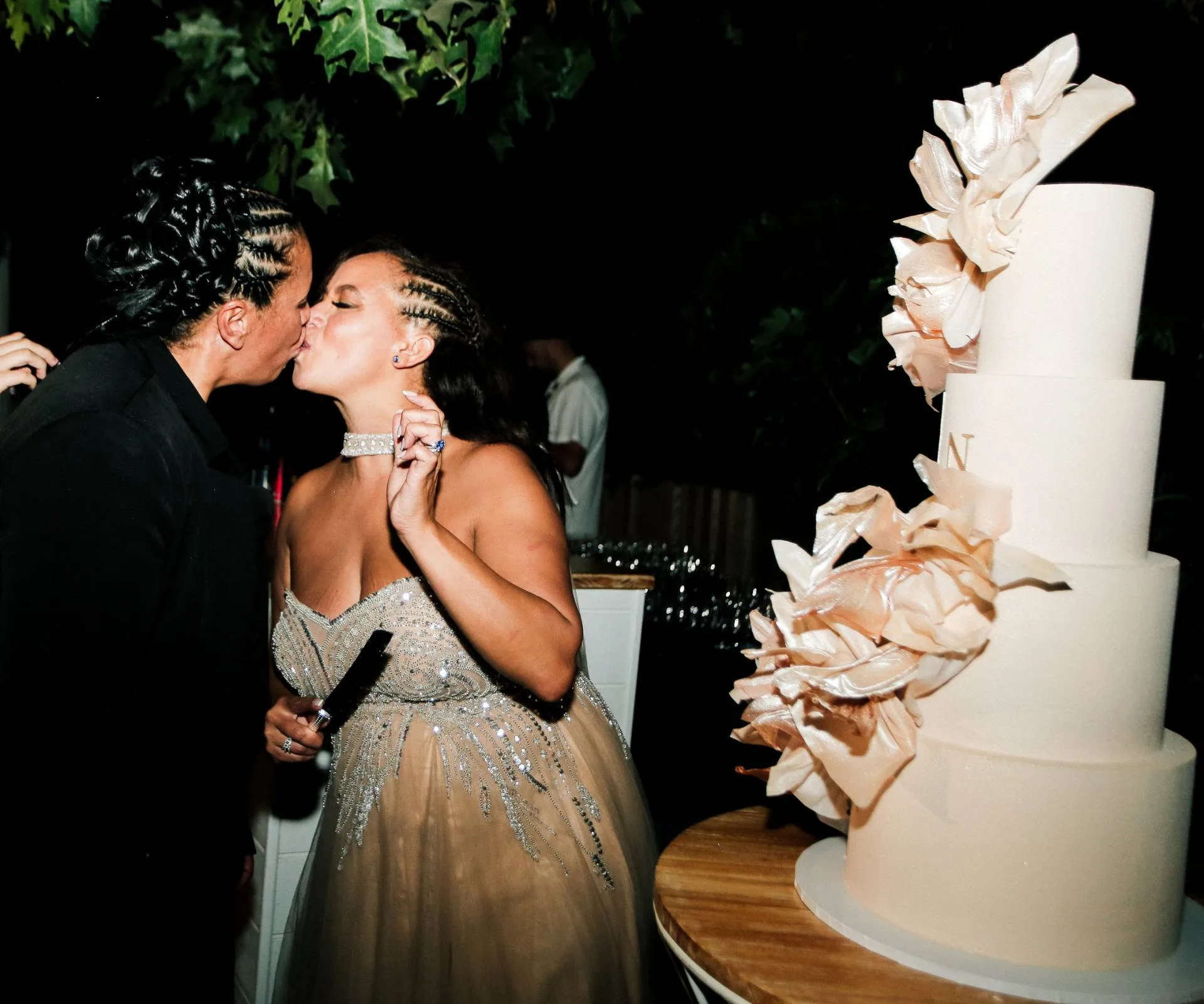 Sharing a kiss beside their wedding cake