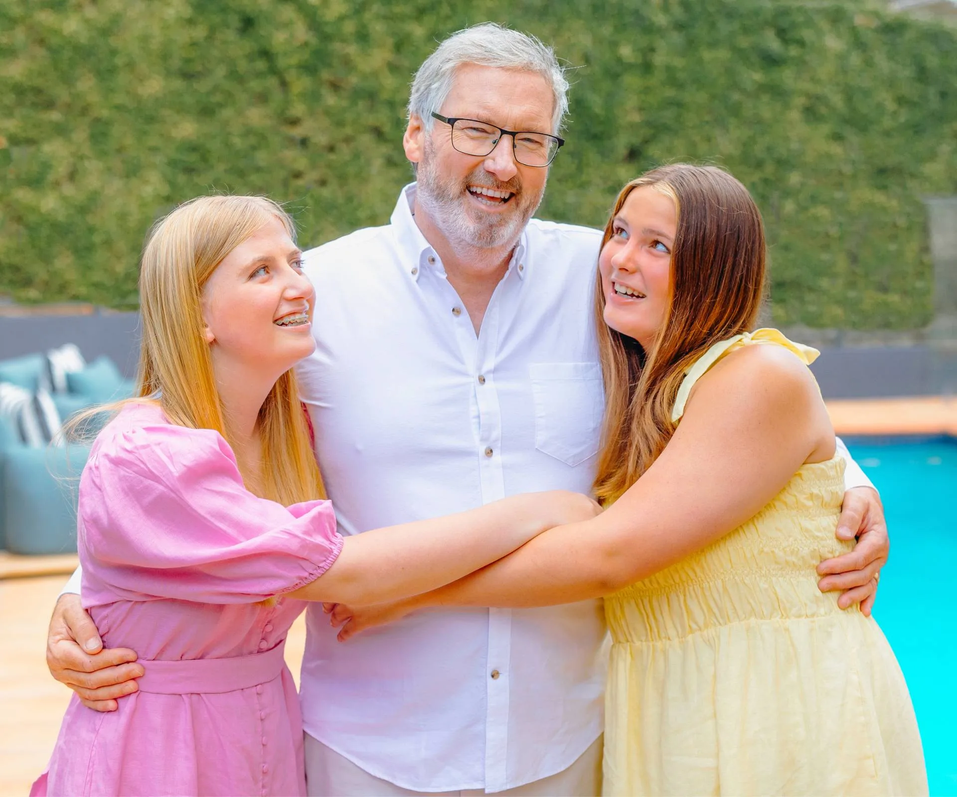 Hugging his daughters in front of the family pool