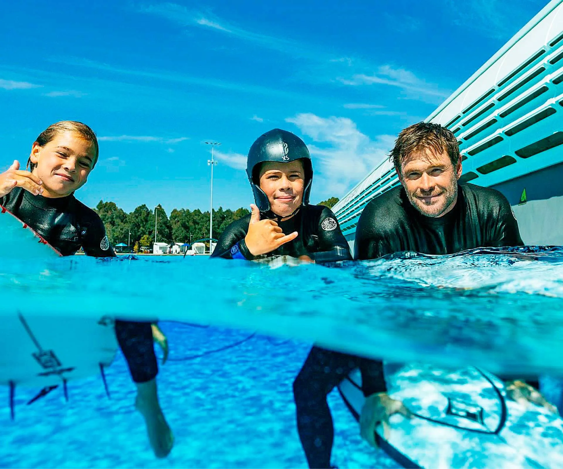 Chris Hemsworth on surfboards in a swimming pool with his sons
