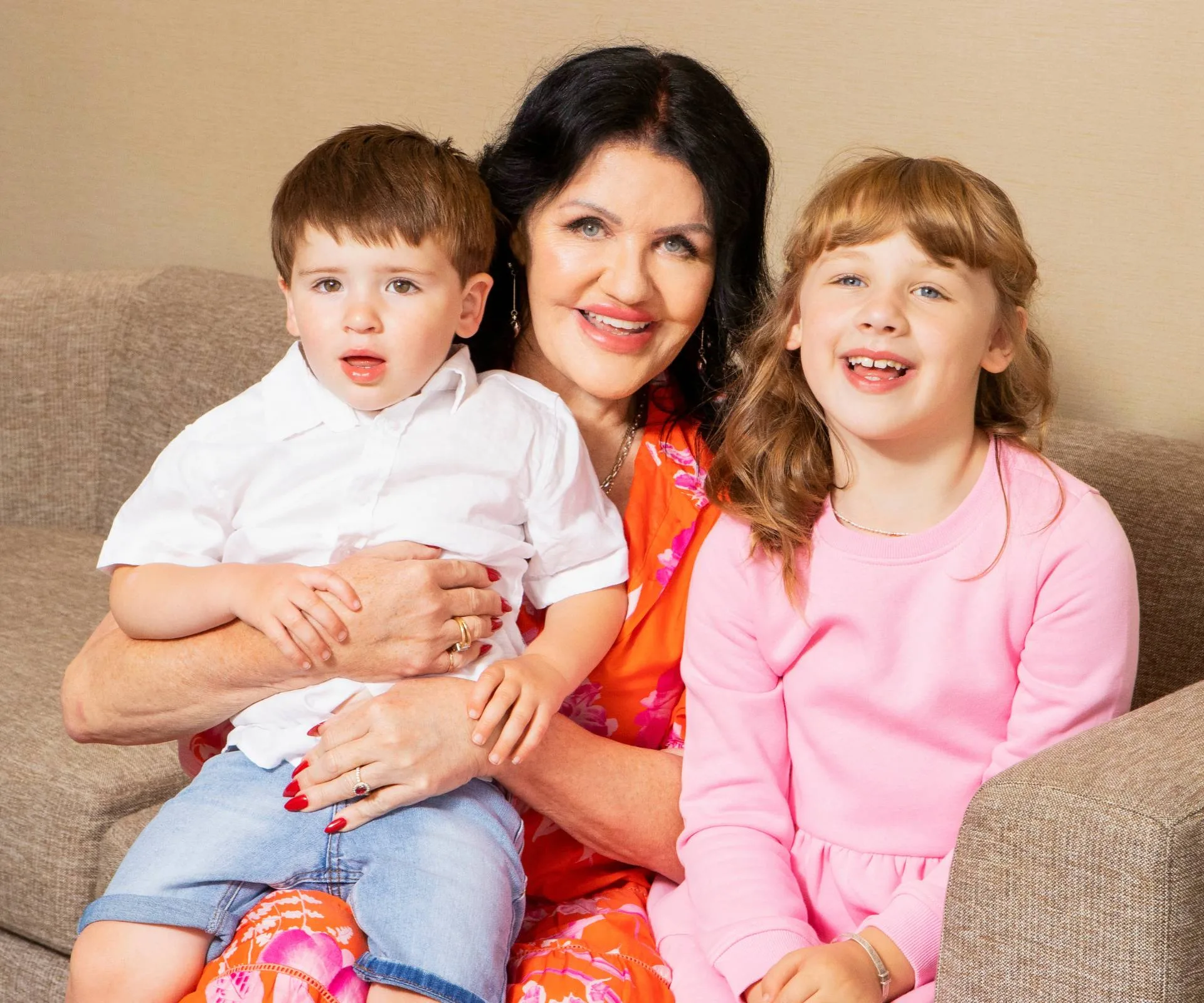 Polly Gillespie sitting on a couch with her two grandchildren