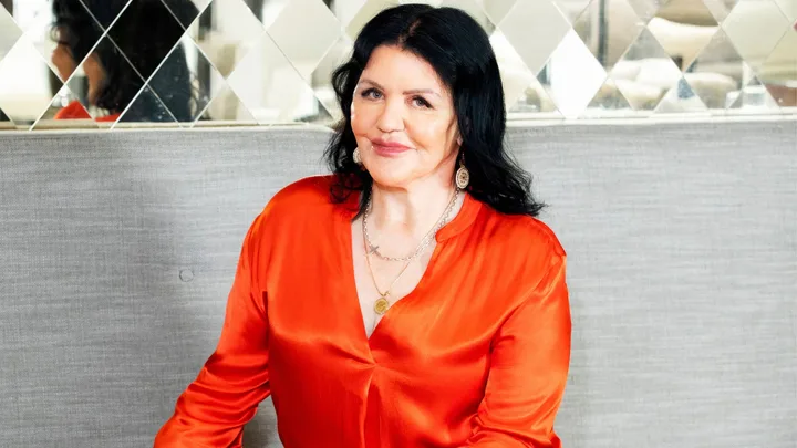Polly Gillespie smiling in a bright orange shirt