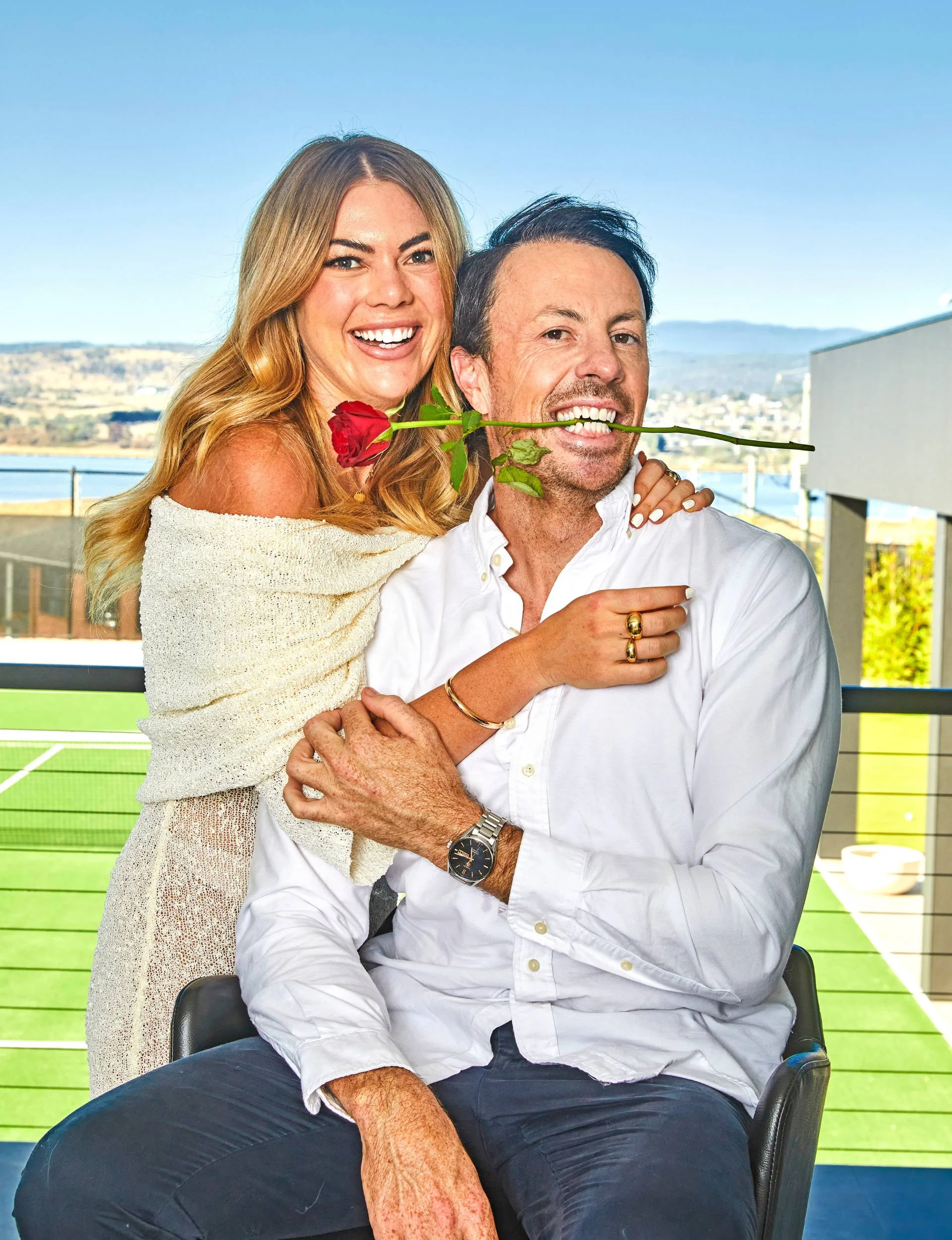 Jacqui and Clint on a balcony, Clint is holding a rose in his mouth