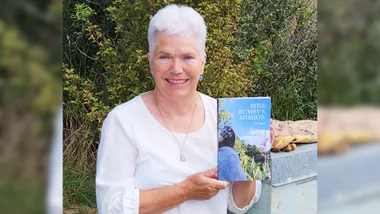 Josie Laird holding up her book about bees, Miss Bumby's Mission