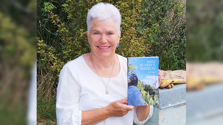 Josie Laird holding up her book about bees, Miss Bumby's Mission