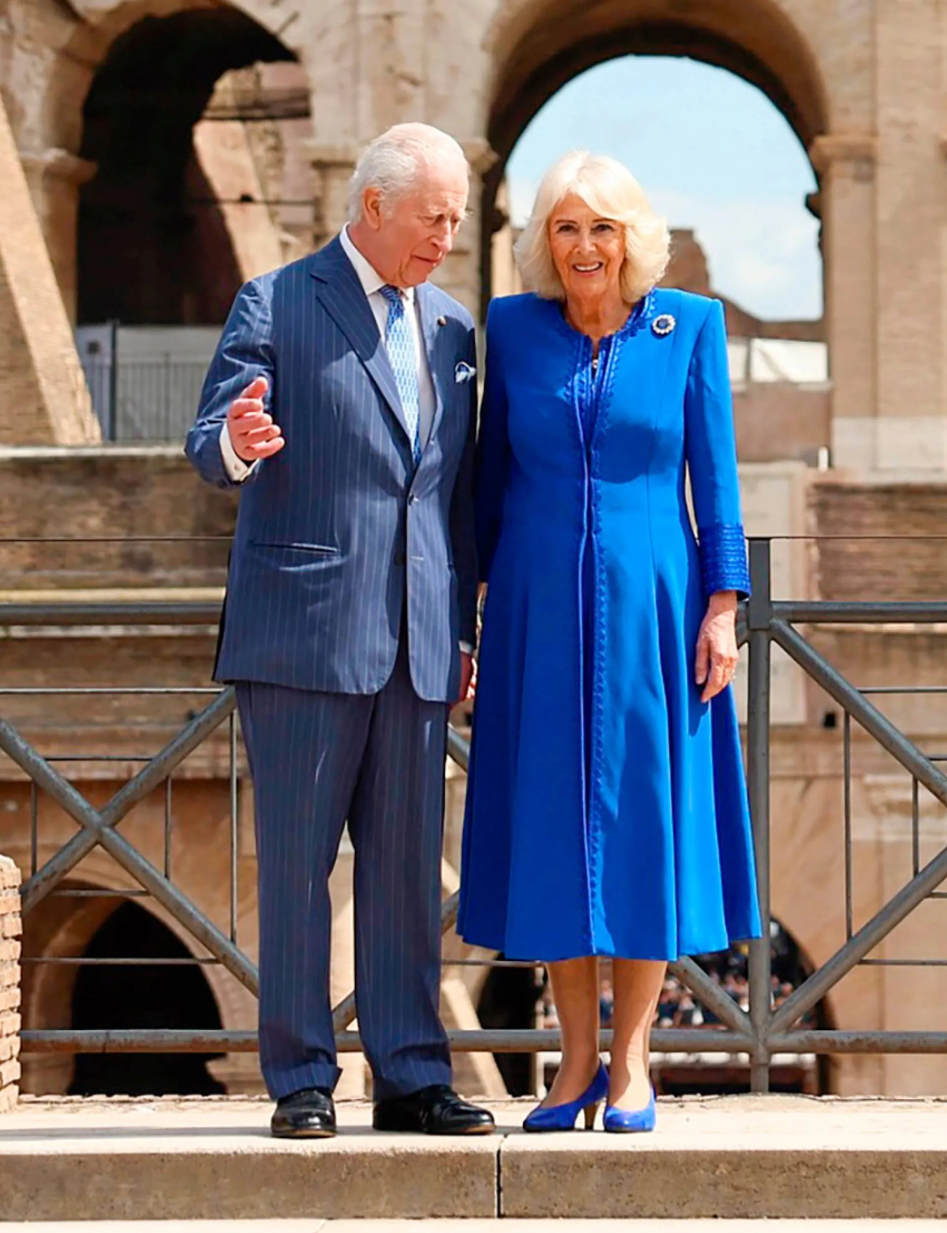 King Charles and Queen Camilla looking over a crowd from an old building