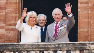 King Charles and Queen Camilla waving from a balcony