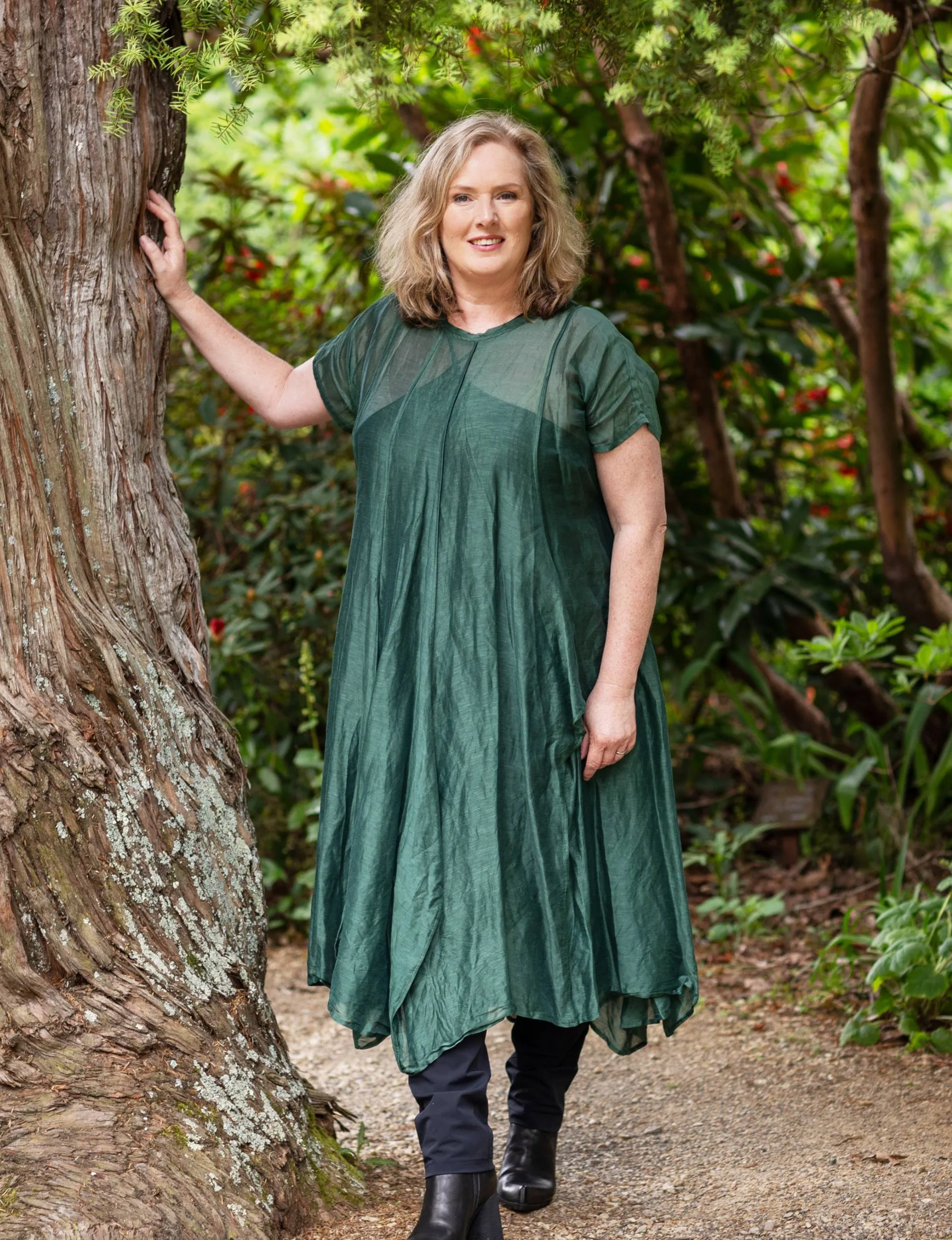 Lara Macgregor leaning against a tree in an emerald green dress