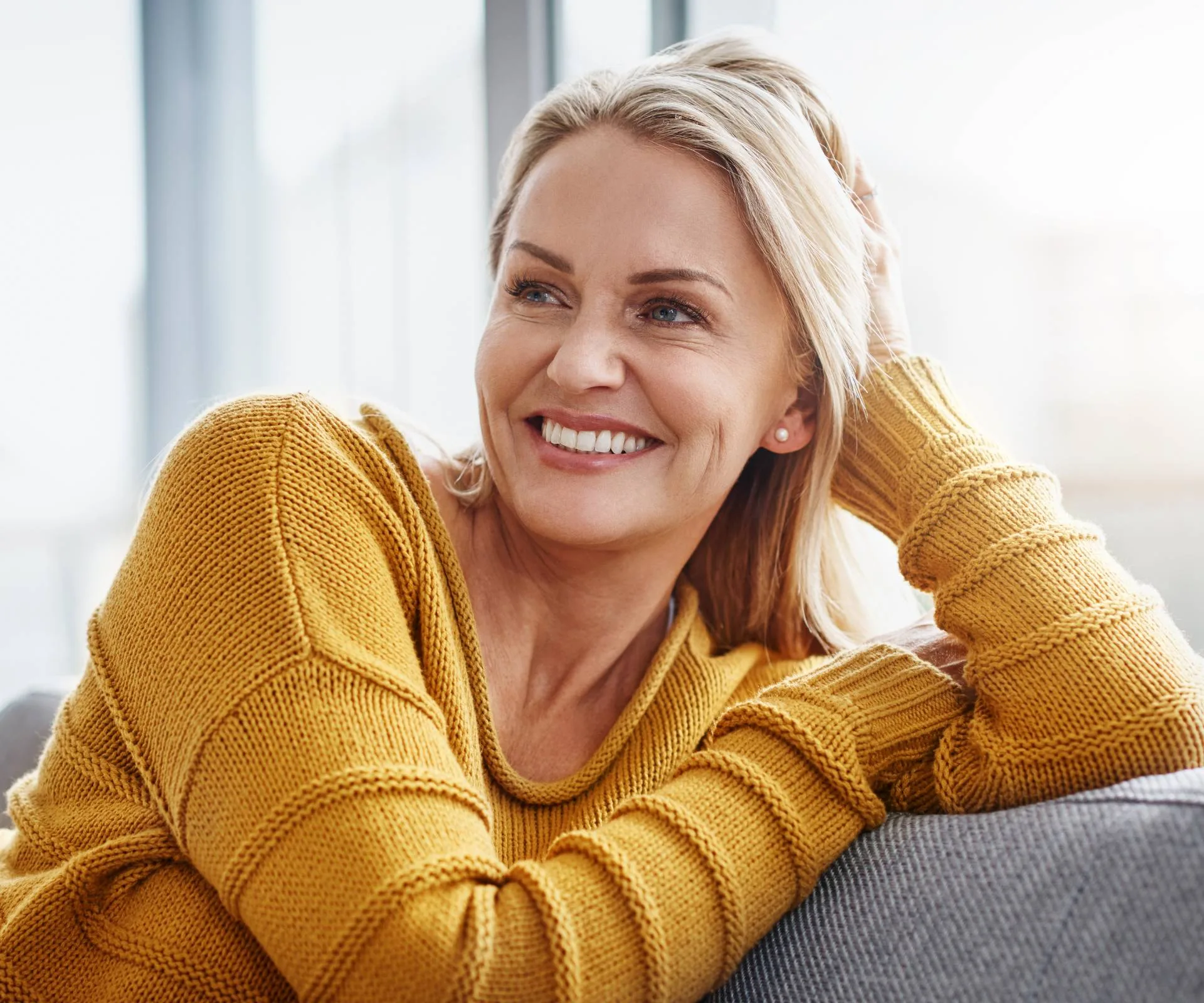 A woman smiling on a grey couch