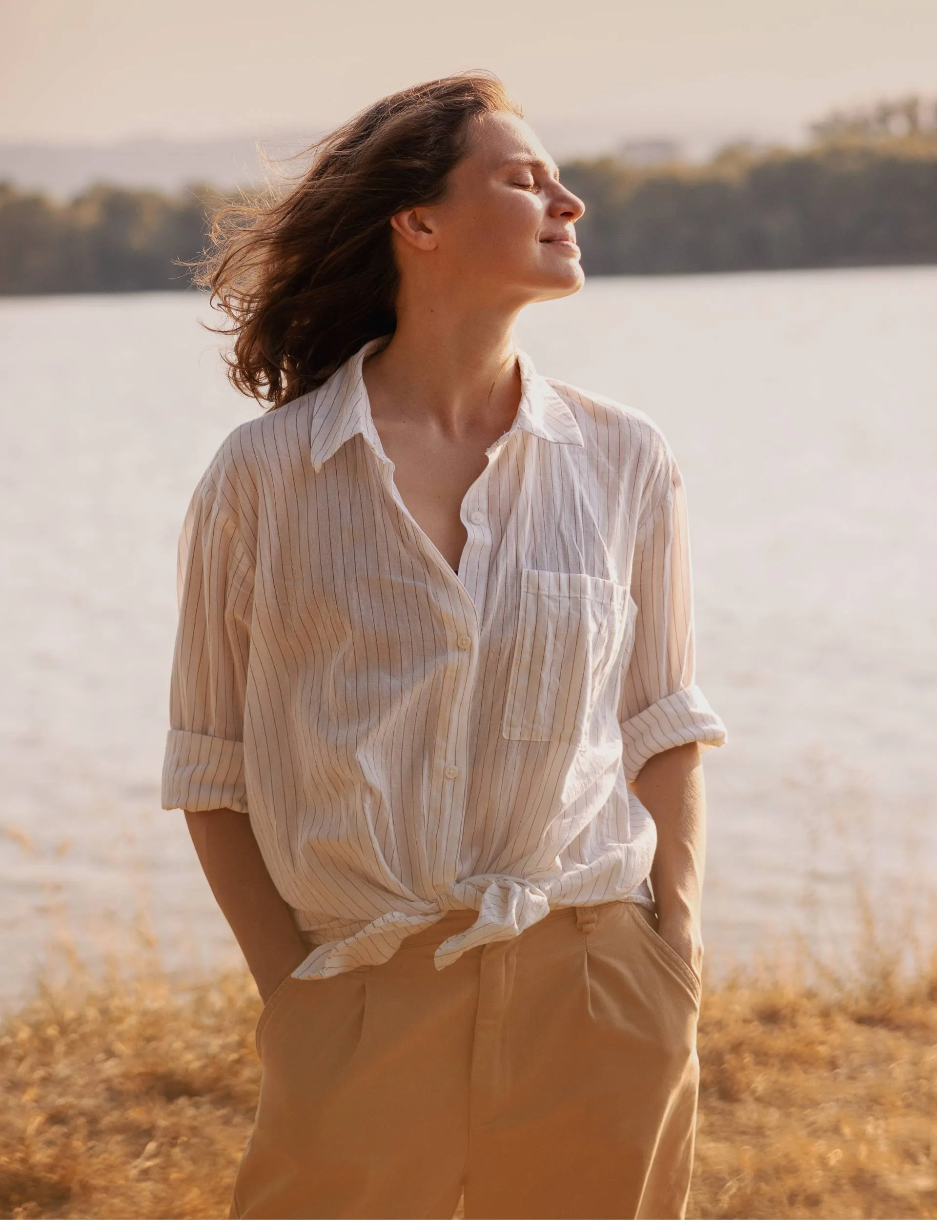 A woman manifesting as she stands beside a river