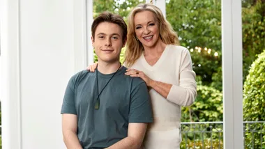 Rebecca Gibney standing beside her son, Zac sitting on the arm of a couch
