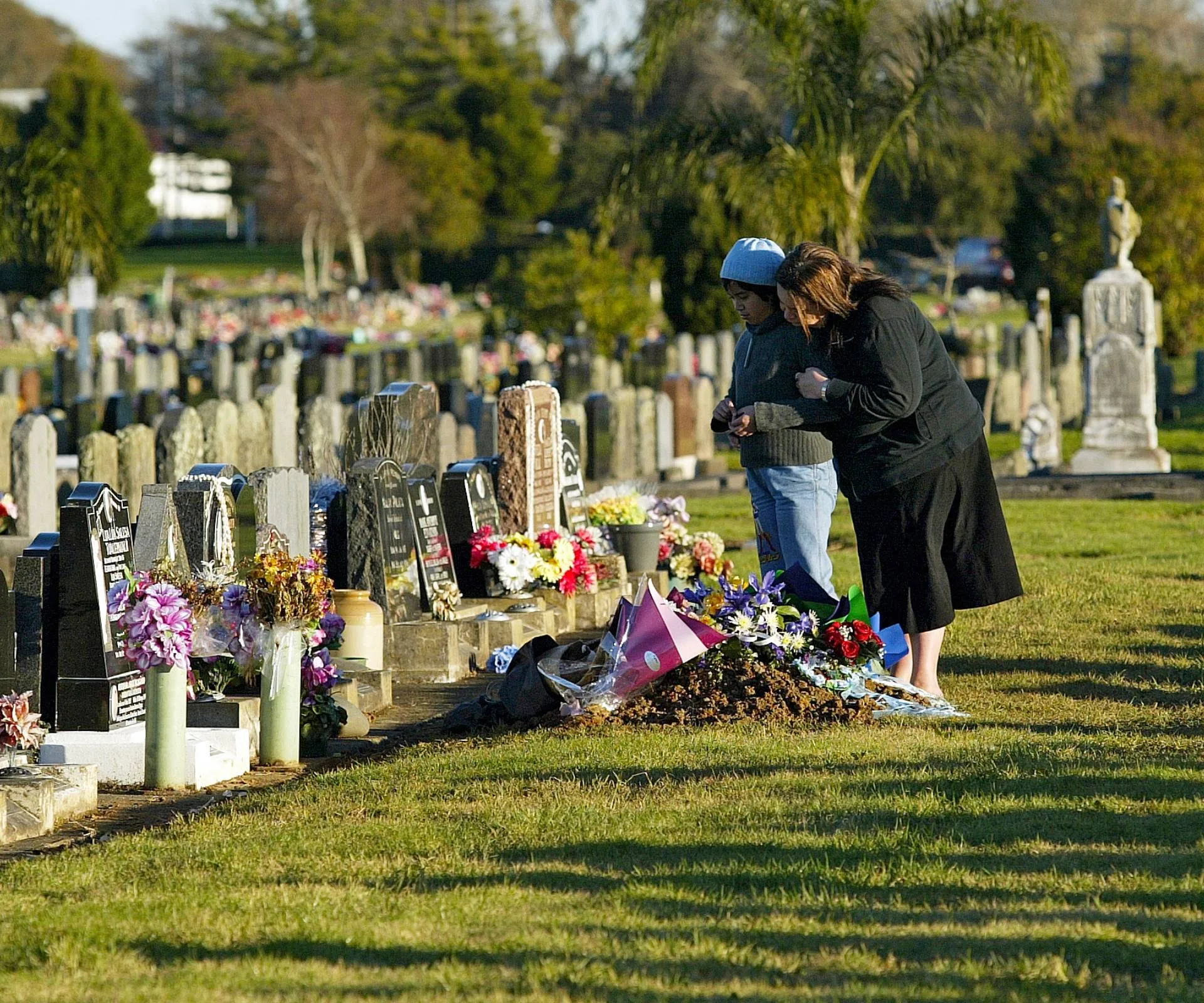 People mourning beside a grave