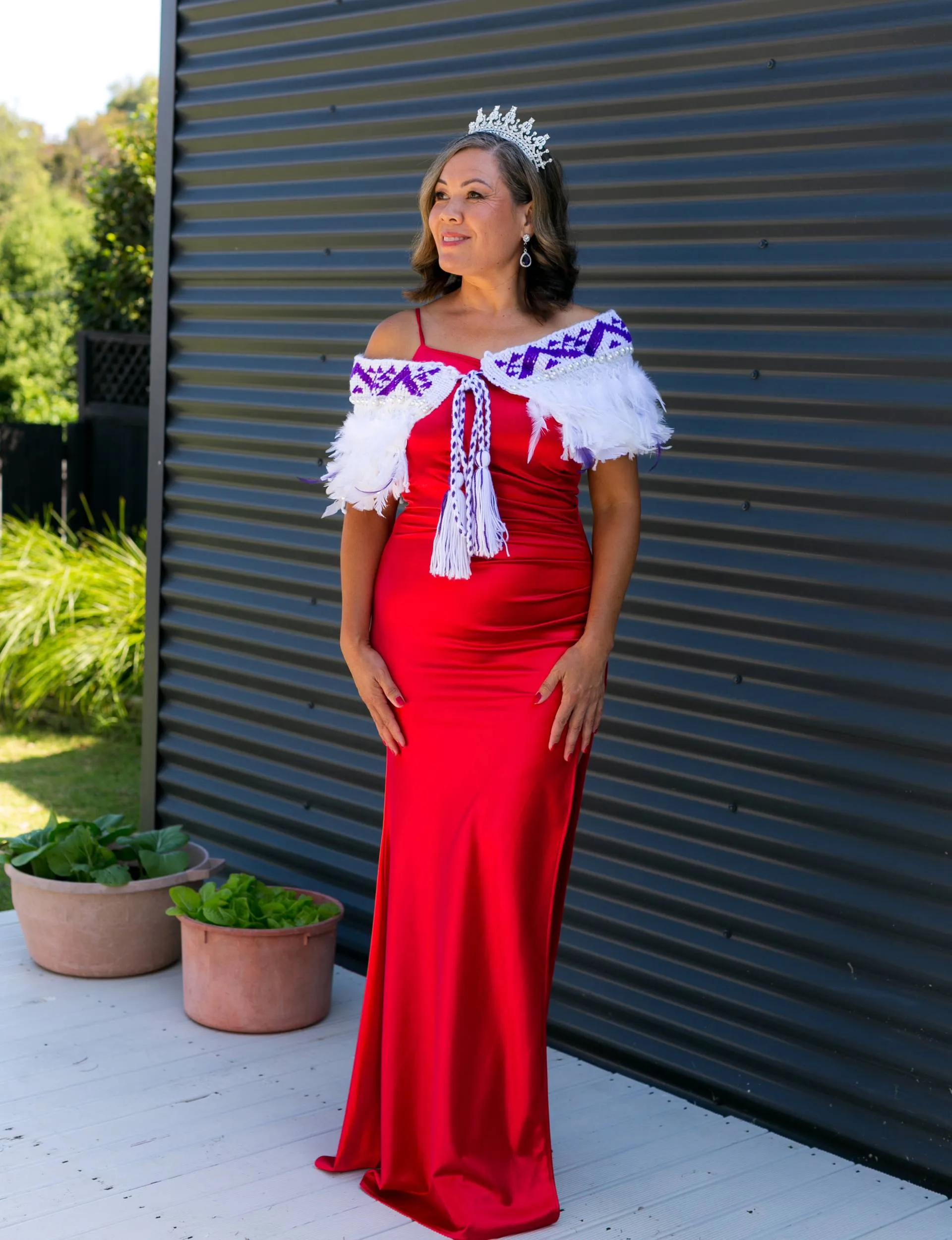 Standing in an elegant red gown, with her Miss Aotearoa sash and crown on