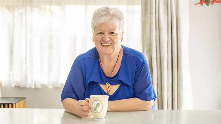 Jo Duston sitting at her kitchen counter with a cup of tea