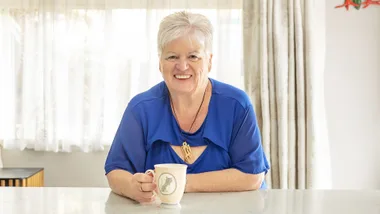 Jo Duston sitting at her kitchen counter with a cup of tea