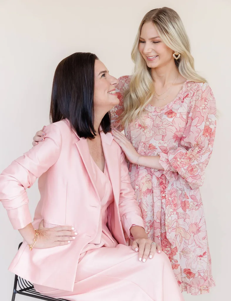 Mother and daughter dressed in pink in front of beige background