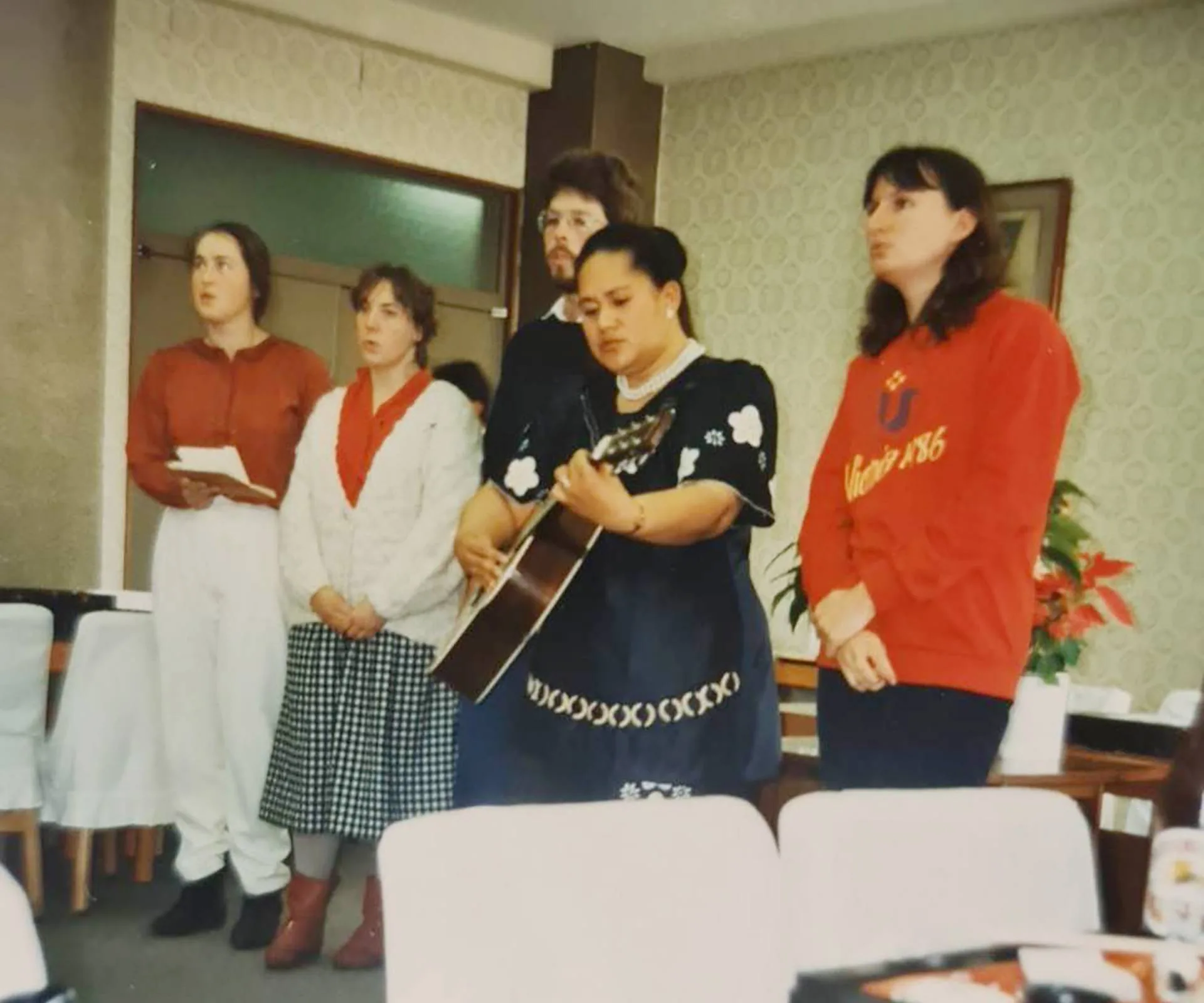 Bella's mother playing the guitar and singing with a community group