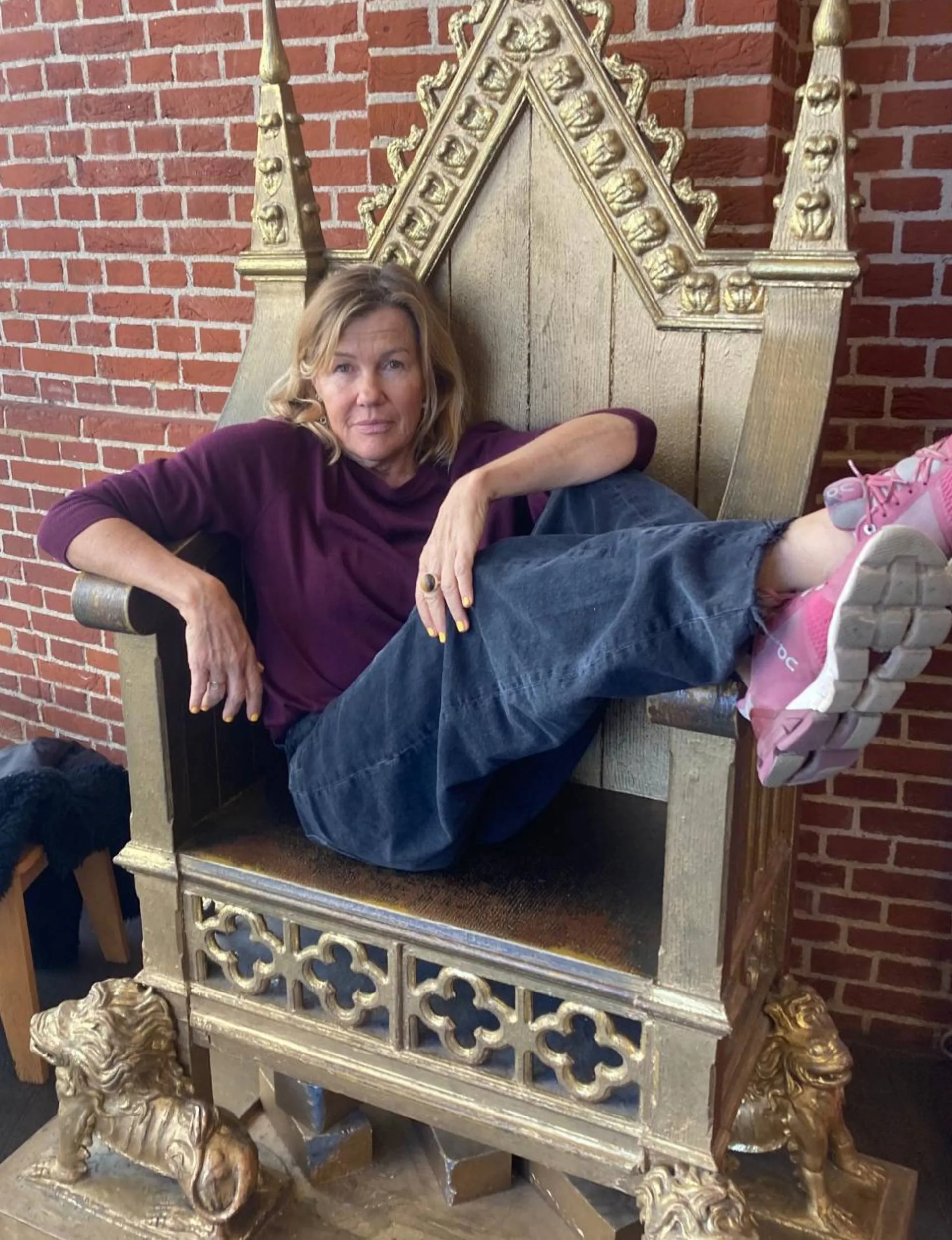 Robyn laying sideways on a large wooden throne