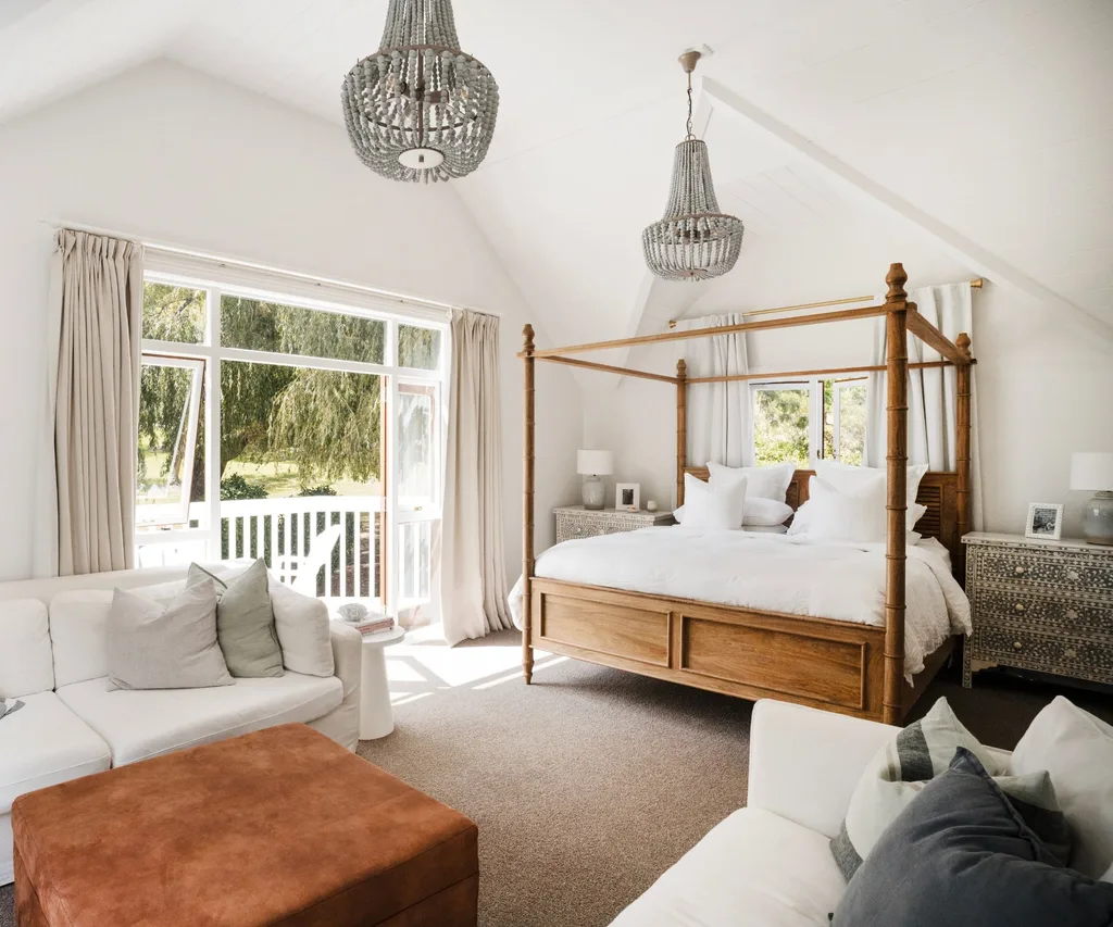 The master bedroom, painted in Resene Black White, is a haven of tranquillity, featuring crisp white linen chairs to lounge in, soft, neutral tones and a four-poster bed