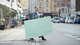 Lady walking across the street holding giant paper shopping bag