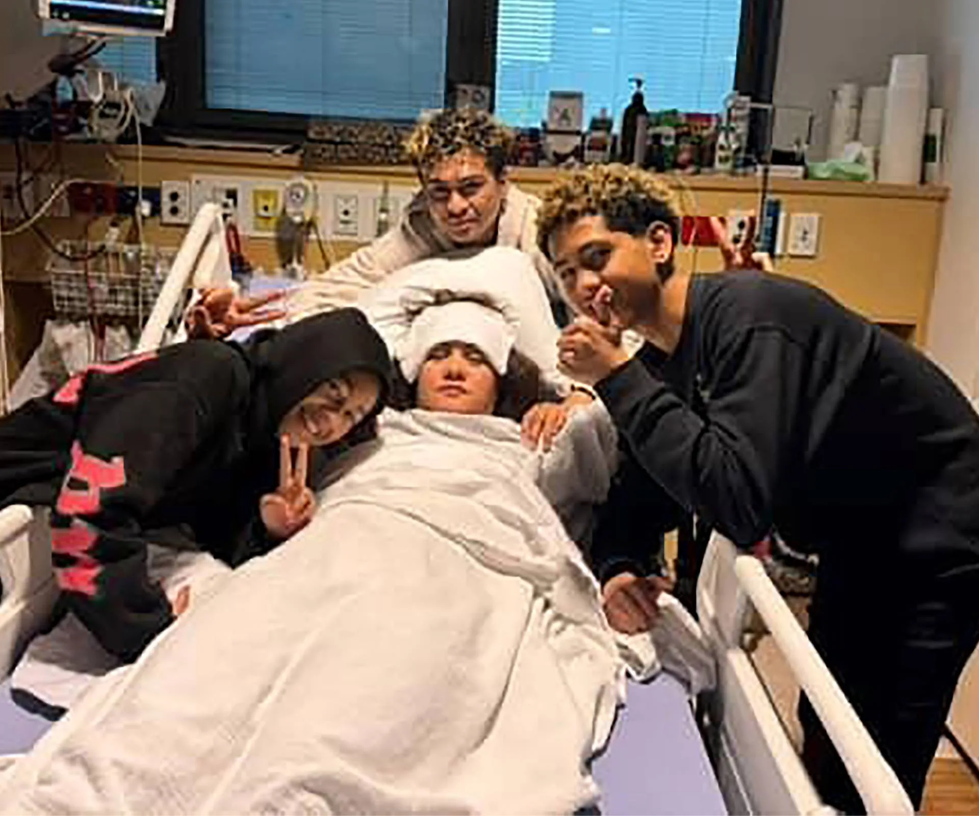 Rangi-Arahina Renee Daniels in a hospital bed surrounded by her kids