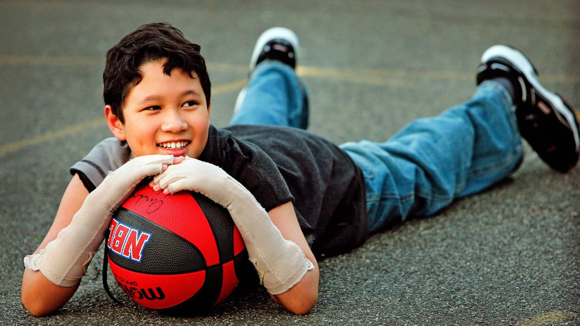 Terry laying on a basketball court, holding a ball