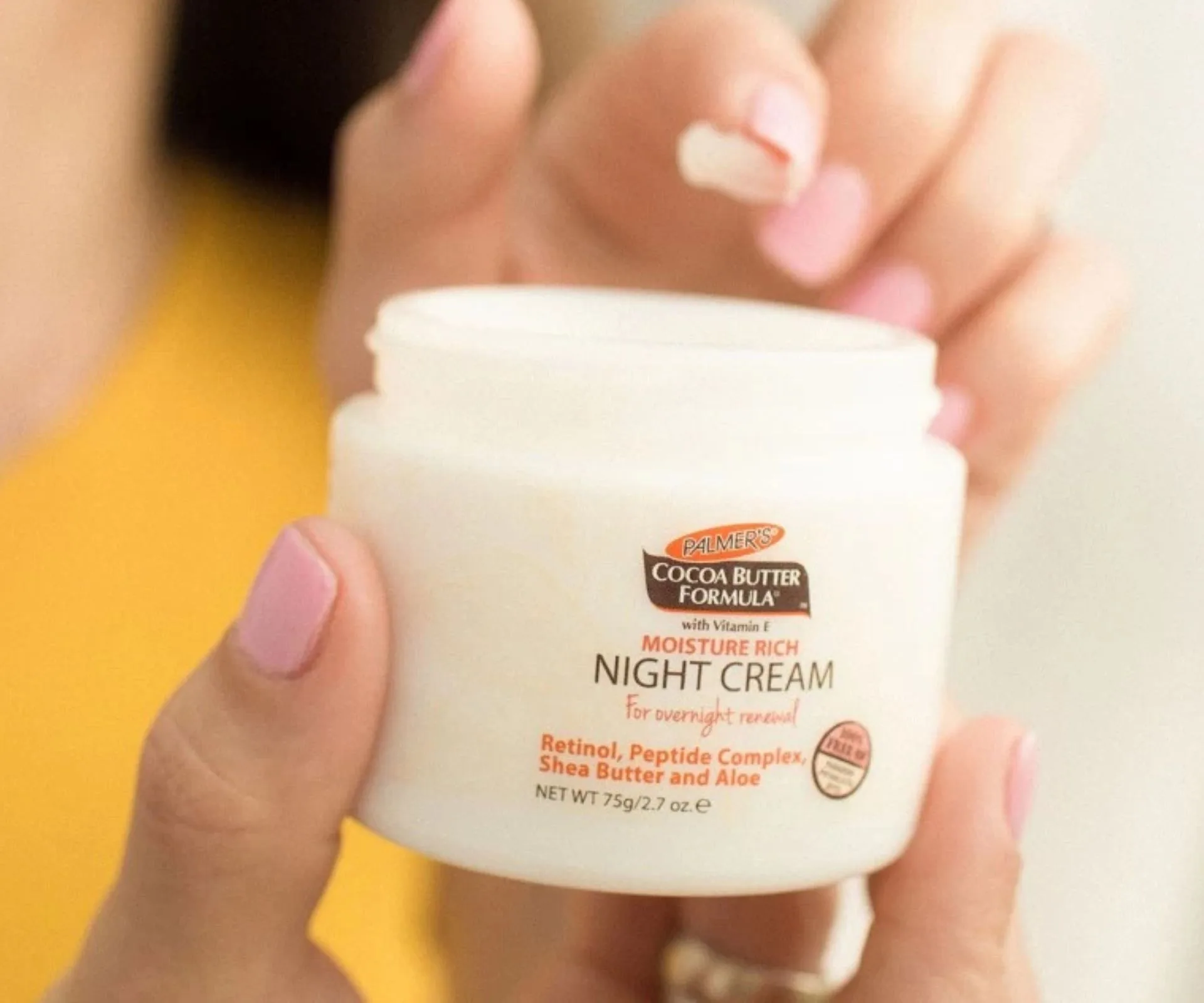 A woman dipping into a pot of Palmer's night cream 