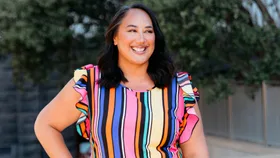 Kerrin Leoni smiling in a rainbow dress